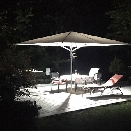 Eine Terrasse mit einem Tisch und Stühlen unter einem Sonnenschirm im Garten.