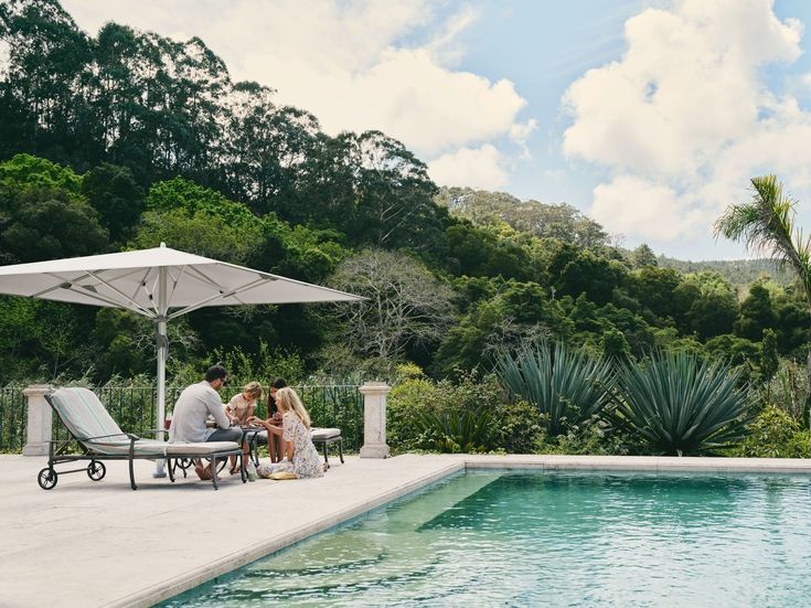 Castello Pro Schirm über Liegen und Familie neben Pool